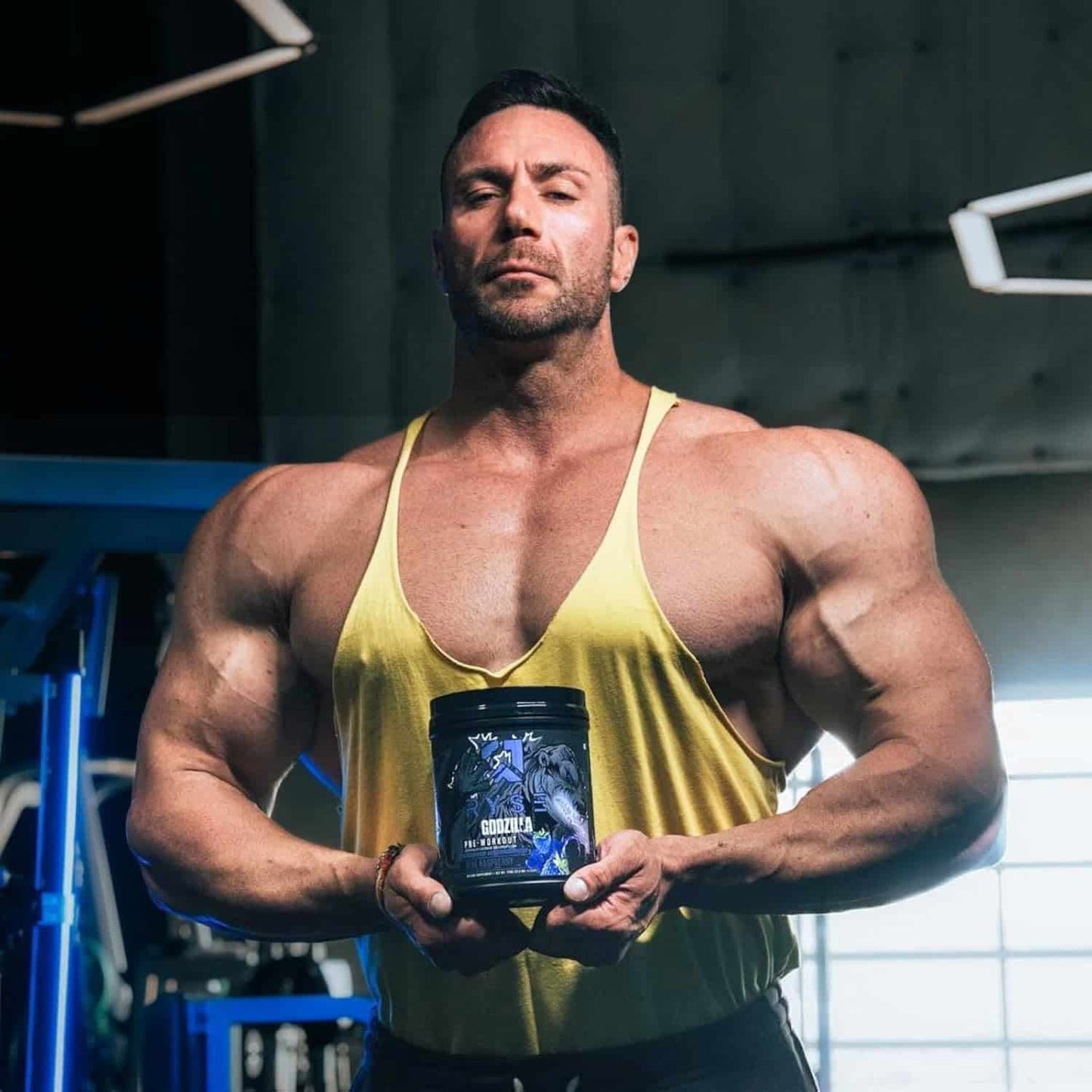 Muscular man holding a supplement container in a gym setting