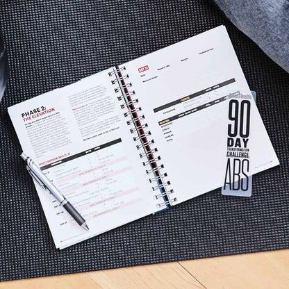 Open planner with fitness challenge pages on a black mat