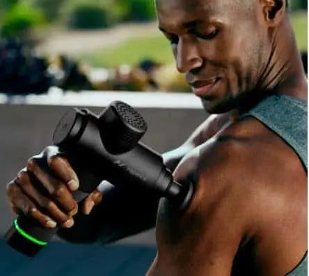 Person using a black massage gun outdoors