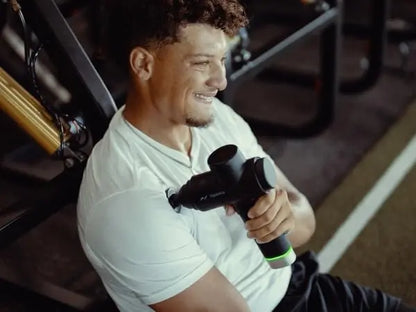 Man using a massage gun in a gym setting