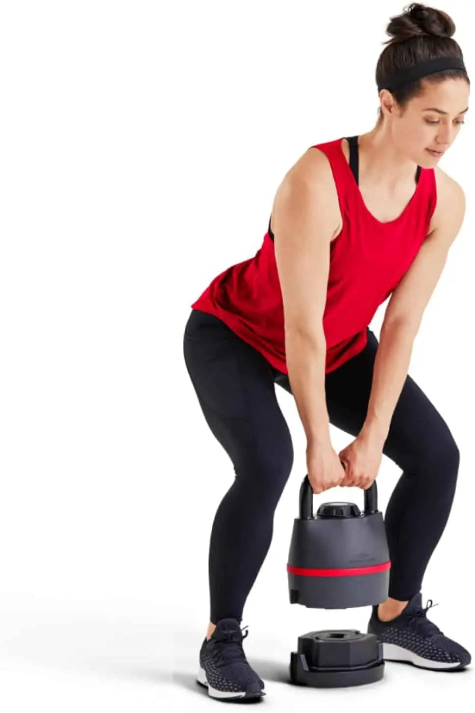 Woman in red tank top and black leggings lifting a black and red kettlebell.