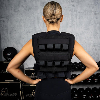 Person wearing a black weighted vest in a gym setting