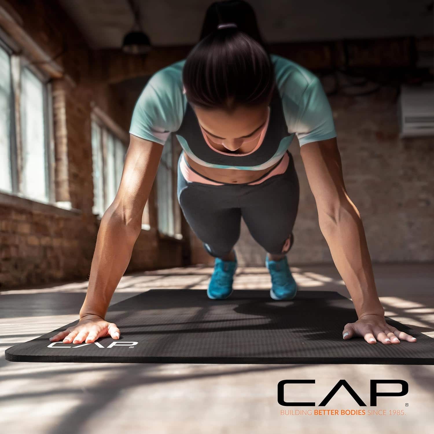 Woman doing push-ups on a CAP branded mat in a gym setting
